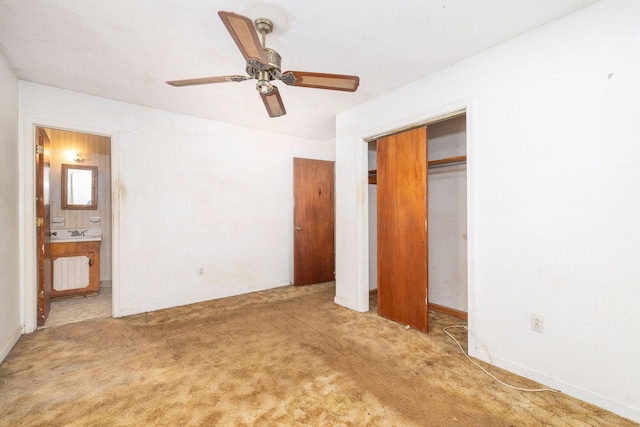 unfurnished bedroom featuring connected bathroom, sink, light colored carpet, ceiling fan, and a closet