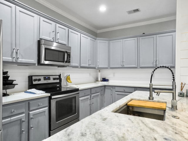 kitchen with gray cabinetry, sink, light stone countertops, and appliances with stainless steel finishes