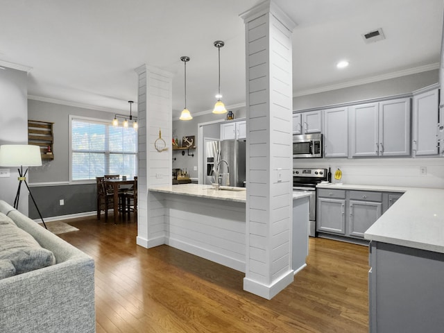 kitchen featuring decorative light fixtures, gray cabinetry, ornamental molding, light stone counters, and stainless steel appliances