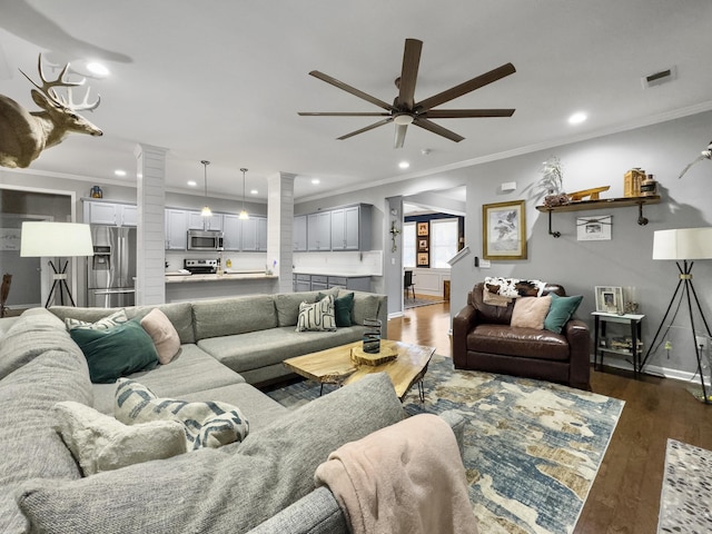 living room with dark wood-type flooring, ceiling fan, ornamental molding, and decorative columns