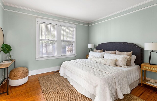bedroom featuring hardwood / wood-style floors, ornamental molding, and baseboards