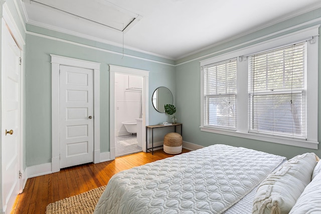 bedroom with attic access, ornamental molding, baseboards, hardwood / wood-style floors, and ensuite bathroom