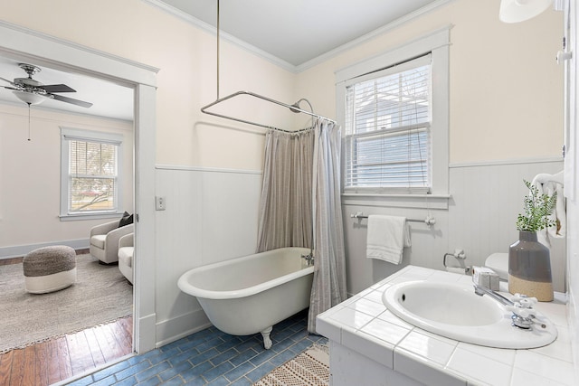 bathroom with a wainscoted wall, ornamental molding, ceiling fan, a soaking tub, and tile patterned flooring