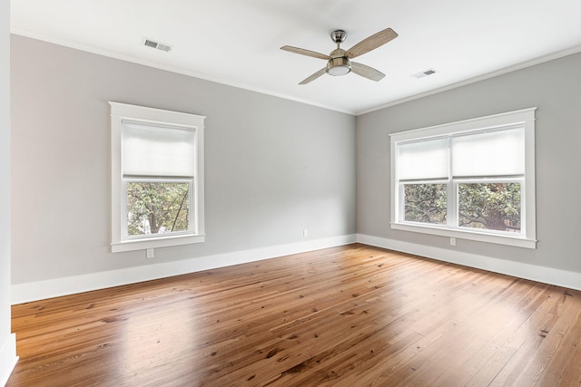 spare room with plenty of natural light, crown molding, hardwood / wood-style floors, ceiling fan, and baseboards
