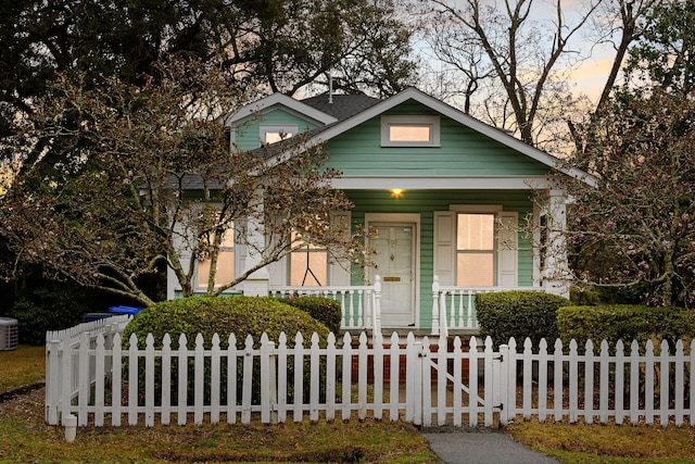 view of front of house with covered porch, a fenced front yard, central AC, and a gate