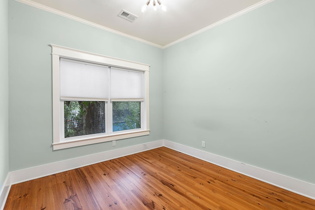 empty room featuring crown molding, baseboards, and wood-type flooring