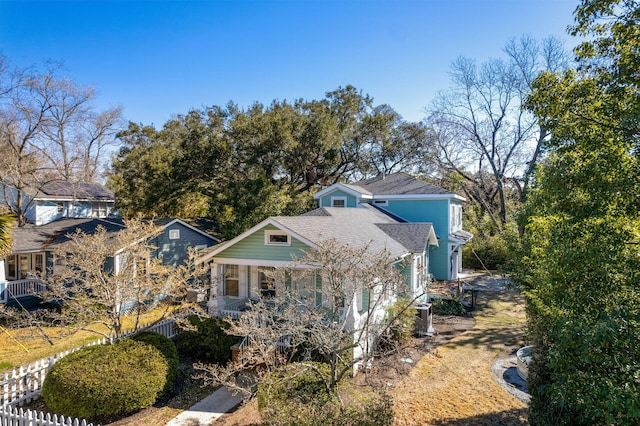 view of front of property with covered porch, roof with shingles, and fence