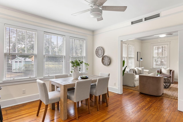 dining space featuring wood-type flooring, a ceiling fan, baseboards, and ornamental molding
