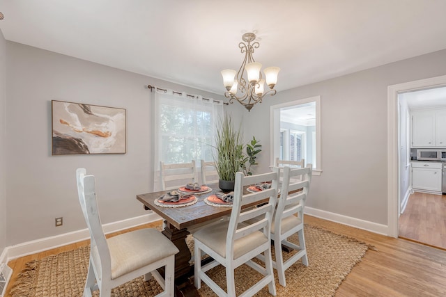 dining space with baseboards, a chandelier, a wealth of natural light, and light wood-type flooring