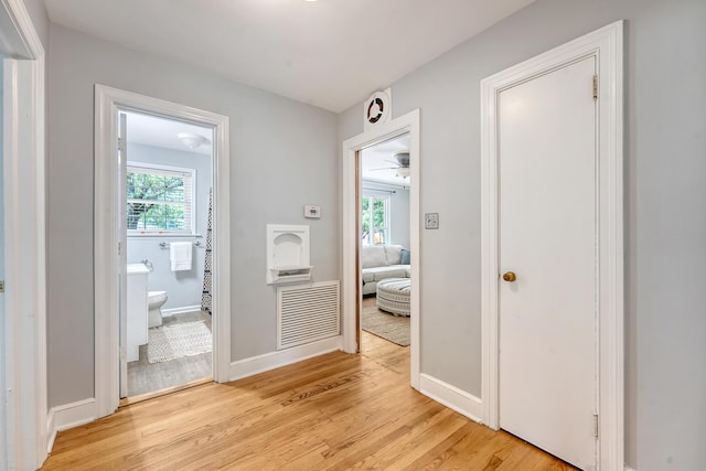 corridor with visible vents, light wood-style floors, plenty of natural light, and baseboards