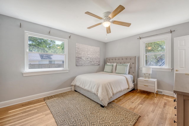 bedroom featuring a ceiling fan, baseboards, visible vents, and wood finished floors
