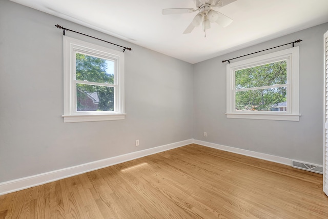 empty room with baseboards, plenty of natural light, light wood finished floors, and visible vents