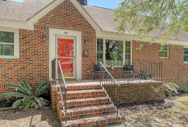 property entrance with brick siding and roof with shingles