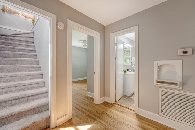 staircase with a ceiling fan, baseboards, and wood finished floors