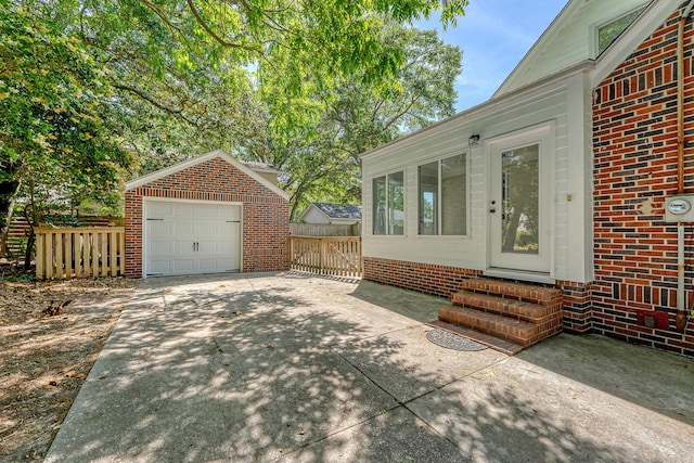 view of patio / terrace with driveway, an outbuilding, a detached garage, fence, and entry steps