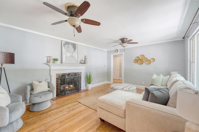 living room featuring ceiling fan, a fireplace, ornamental molding, and wood finished floors
