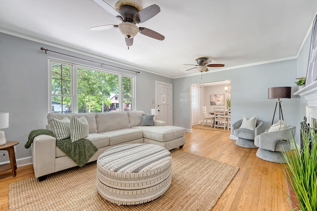 living area with baseboards, ornamental molding, light wood finished floors, and ceiling fan