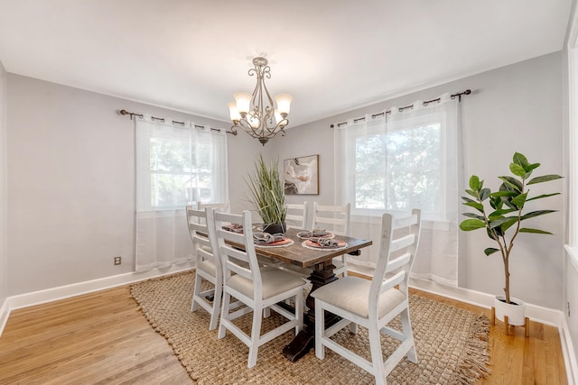 dining space with baseboards, a chandelier, and light wood-style floors