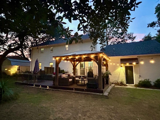 back house at dusk featuring a gazebo, an outdoor living space, and a yard