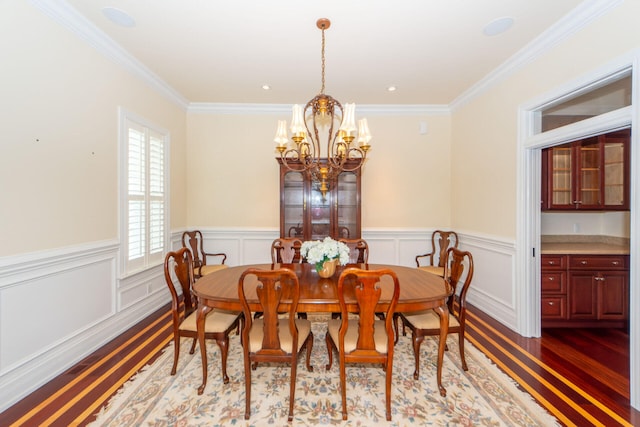 dining area featuring a wainscoted wall, ornamental molding, wood finished floors, and a notable chandelier