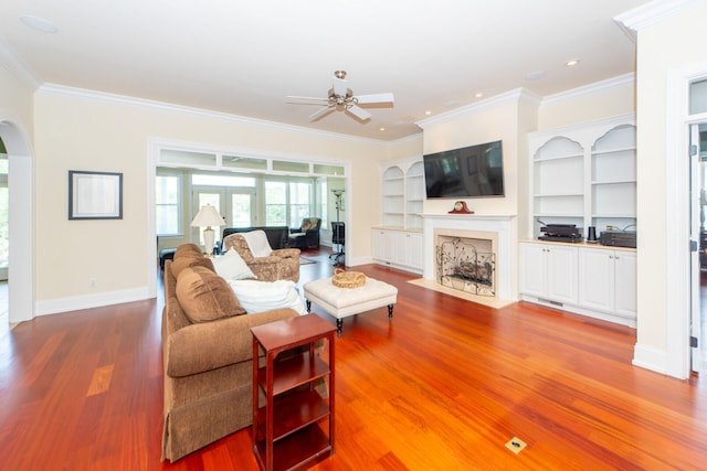 living room with arched walkways, wood finished floors, baseboards, french doors, and ornamental molding