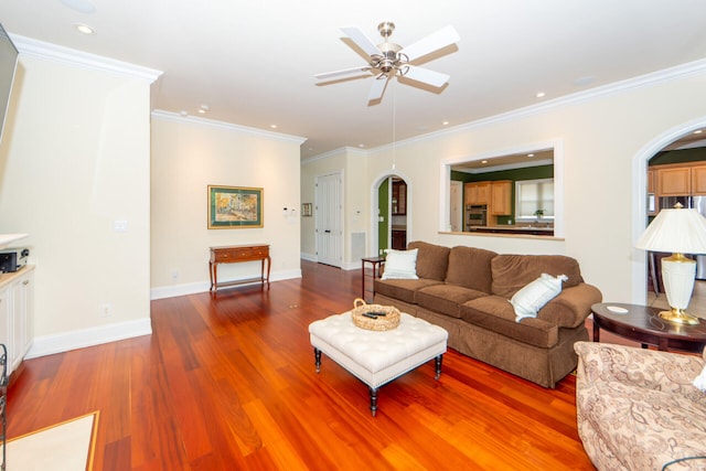 living area featuring baseboards, arched walkways, wood finished floors, and ornamental molding