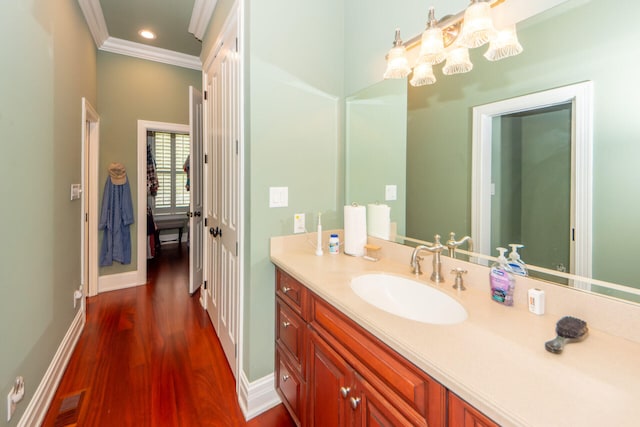 bathroom with crown molding, vanity, baseboards, and wood finished floors