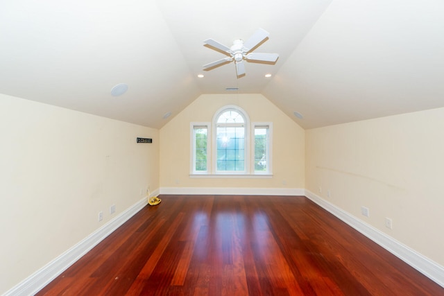 additional living space featuring lofted ceiling, dark wood finished floors, a ceiling fan, and baseboards