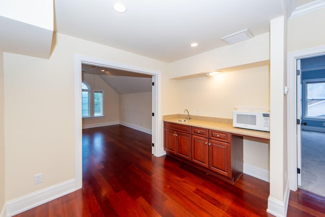 kitchen featuring white microwave, dark wood-style flooring, a sink, visible vents, and light countertops