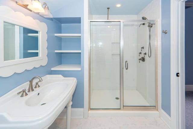 full bathroom featuring marble finish floor, a sink, a shower stall, and baseboards