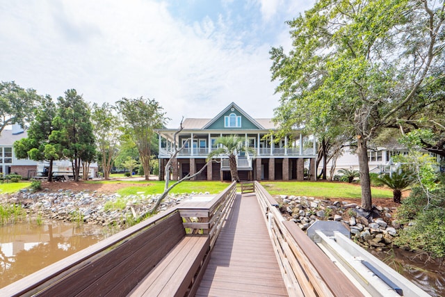 rear view of house featuring a lawn and a deck with water view