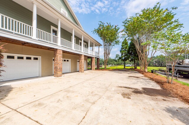 view of side of property featuring a garage, concrete driveway, a balcony, and stucco siding