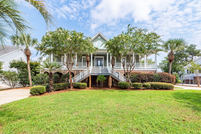 coastal home featuring a front yard, covered porch, driveway, and stairs