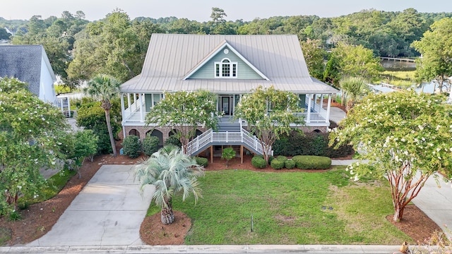 view of front of house with brick siding, a porch, stairway, a front yard, and driveway