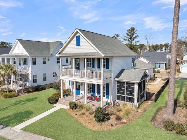 view of front of property with a sunroom, a front yard, a balcony, and covered porch