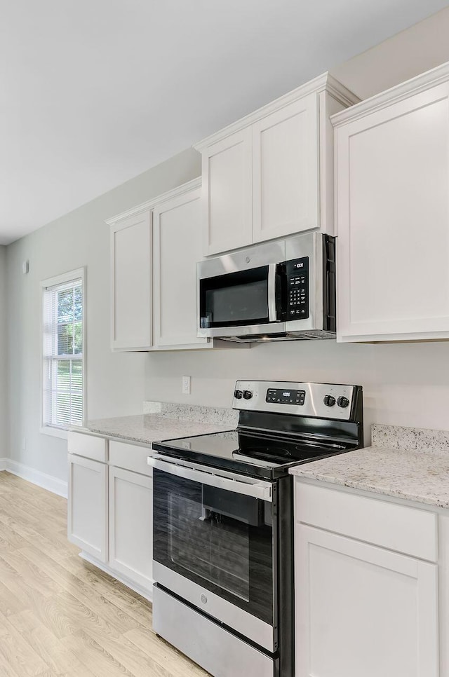 224 Young Town Cir, Orangeburg, SC 29118 - kitchen featuring light stone counters, stainless steel appliances, light wood-style flooring, white cabinets, and baseboards