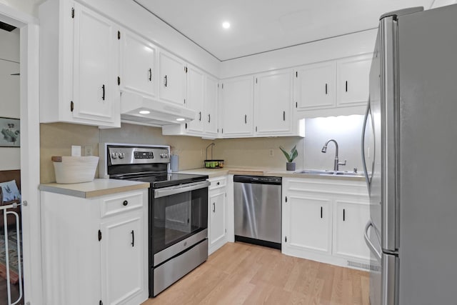 kitchen featuring a sink, light countertops, light wood-style floors, appliances with stainless steel finishes, and under cabinet range hood