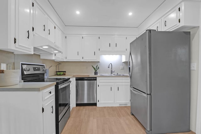 kitchen with light wood finished floors, a sink, stainless steel appliances, light countertops, and under cabinet range hood