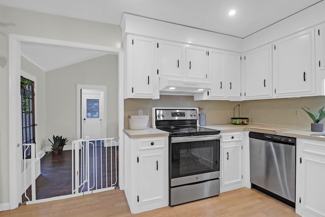 kitchen featuring under cabinet range hood, light wood-type flooring, light countertops, white cabinets, and stainless steel appliances