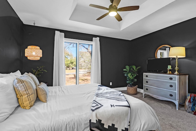 bedroom with a raised ceiling, carpet flooring, baseboards, and ceiling fan