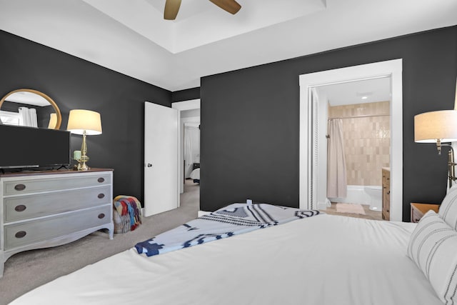 carpeted bedroom featuring ensuite bath and a ceiling fan