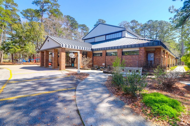 exterior space featuring brick siding, driveway, metal roof, and a standing seam roof