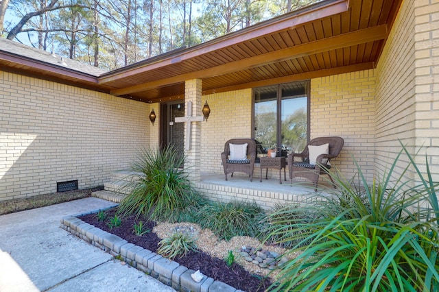 doorway to property featuring crawl space, a porch, and brick siding