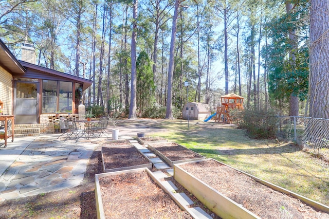 view of yard with fence, a playground, a patio, and a garden