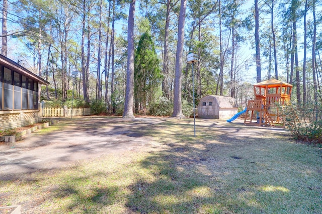 view of yard with an outbuilding, a storage unit, a playground, and fence