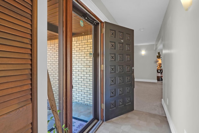 entryway featuring baseboards and light carpet