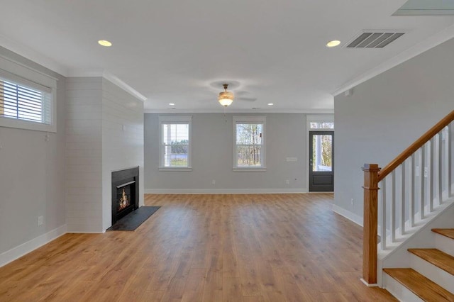 unfurnished living room featuring ceiling fan, a fireplace, light wood-type flooring, and crown molding