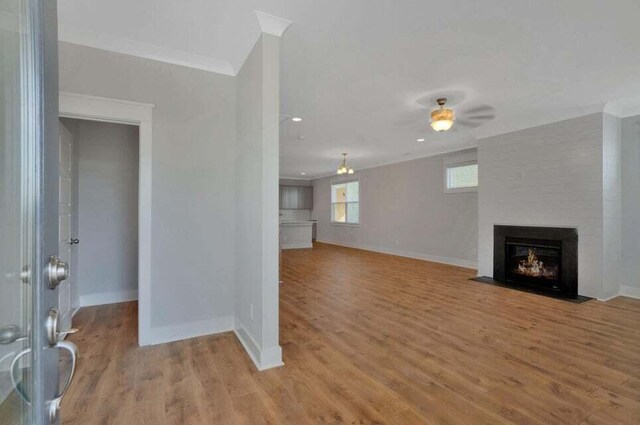 unfurnished living room featuring ornamental molding, light hardwood / wood-style floors, a fireplace, and ceiling fan