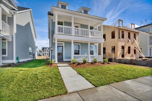 view of front of house featuring a balcony, a porch, and a front lawn