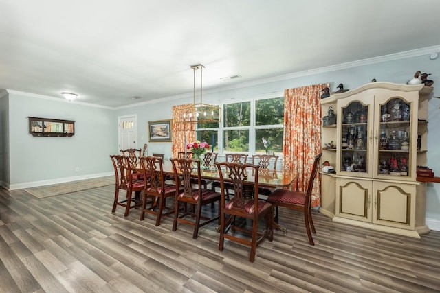 dining area with crown molding, a chandelier, and hardwood / wood-style floors